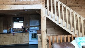 A wooden interior with a kitchen, a staircase, and a leather sofa. - Reid's Hidden River Getaway (Luther)