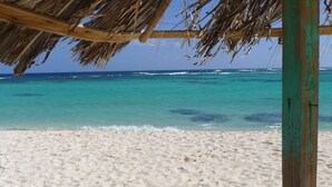 A beach with a thatched roof structure and a wooden post.