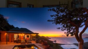 A modern house with a swimming pool, outdoor seating, and a view of the ocean at sunset.