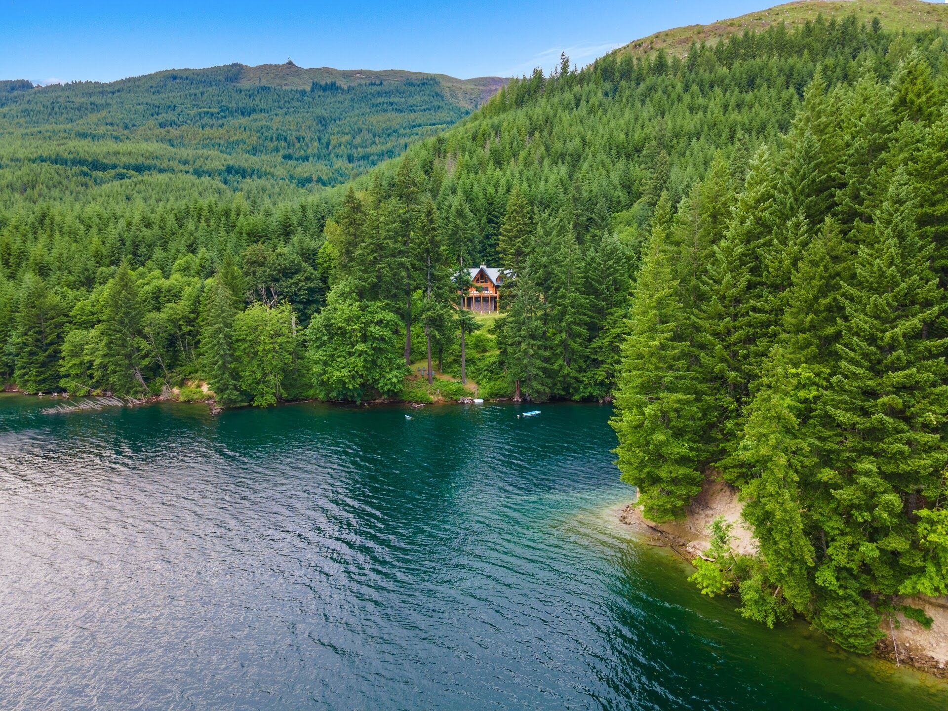A lodge surrounded by dense forest and a lake.