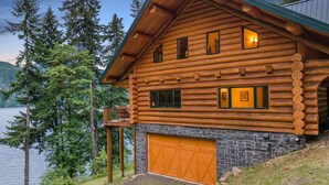 A log cabin with a stone foundation, a wooden deck, and a garage. - Lake front Lodge on Lake Swift (Cougar)