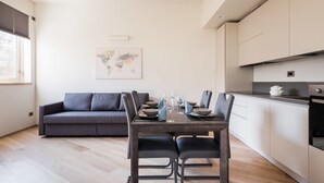 Une cuisine moderne avec une table à manger pour quatre personnes, un canapé gris et une œuvre d’art représentant une carte du monde accrochée au mur.