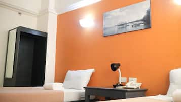 Quarto de hotel com duas camas, uma escrivaninha com abajur, telefone e um quadro na parede.