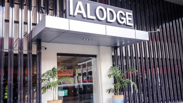 Het uiterlijk van een hotel genaamd IALODGE, met een modern gevelontwerp, een grote glazen ingang en twee plantenpotten ervoor.