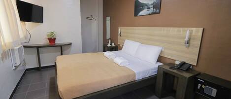 A modern hotel room with a bed, bedside table, TV, and a painting on the wall.