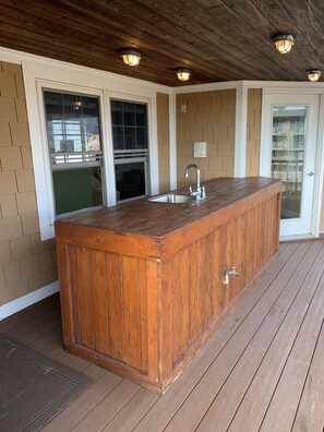 Eine Holzterrasse mit integriertem Barbereich, inklusive Spüle und Wasserhahn.