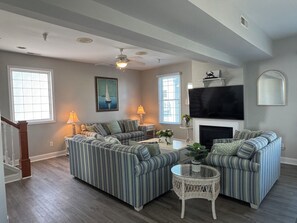 A living room with a sofa set, a fireplace, a television, and a ceiling fan.