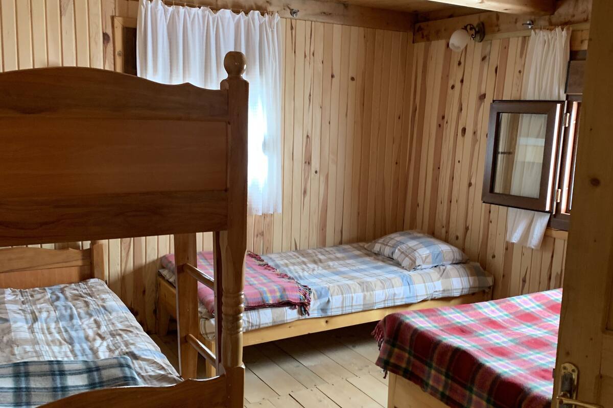 Habitació d'una cabana de fusta amb dos llits superposats, una taula petita i un mirall a la paret.