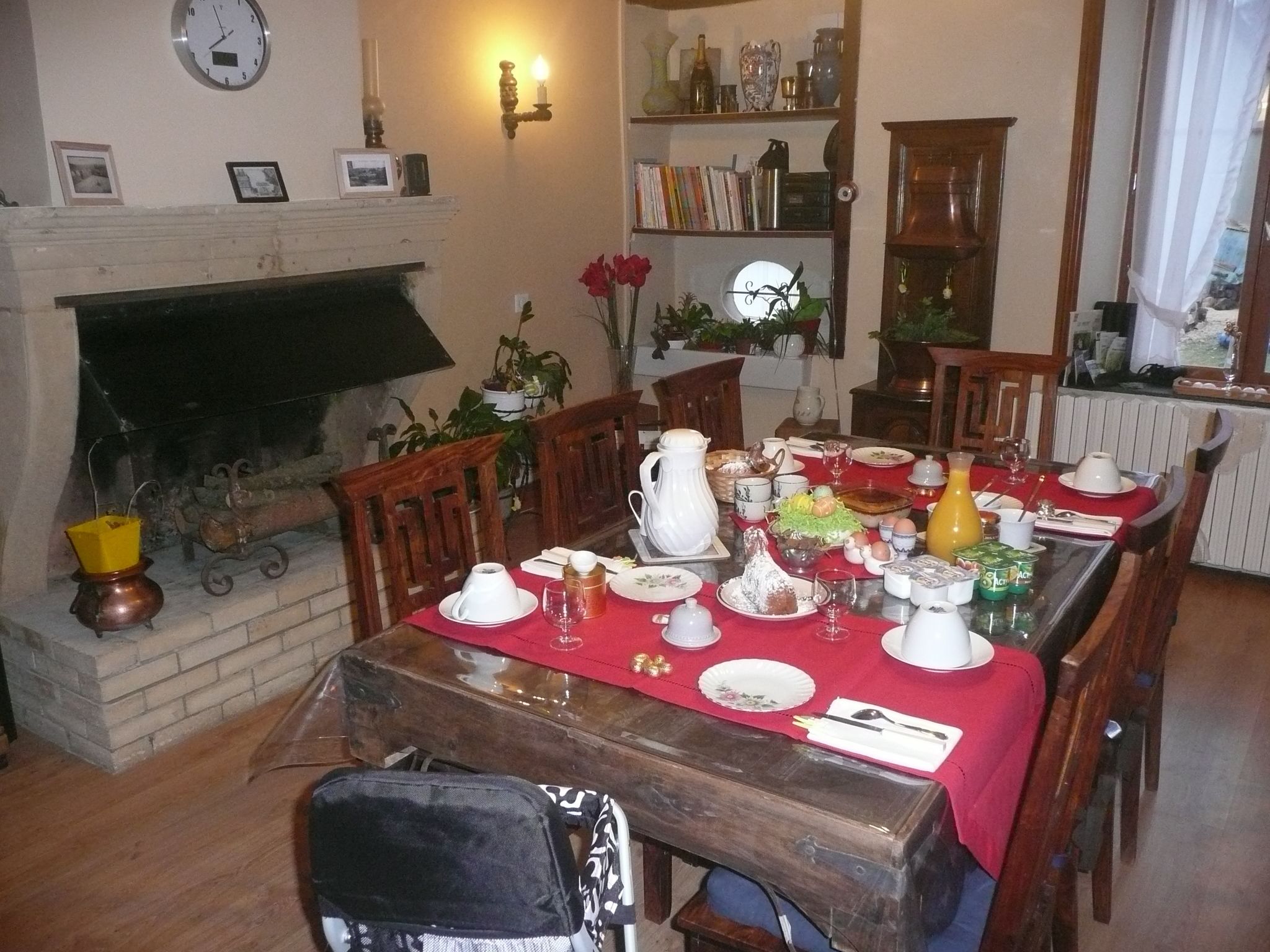 A dining room with a fireplace, wooden furniture, and a red tablecloth.