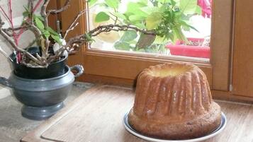 Een bundt cake op een bord, op een houten ondergrond, nabij een raam met een potplant.
