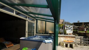 Een hottub met een houten terras en een overdekt patio.