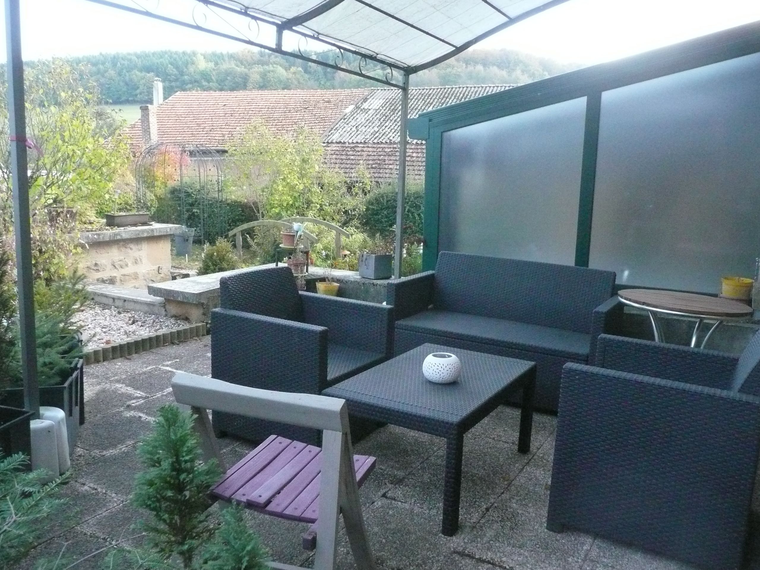 An outdoor patio with wicker furniture, a wooden bench, and a table.