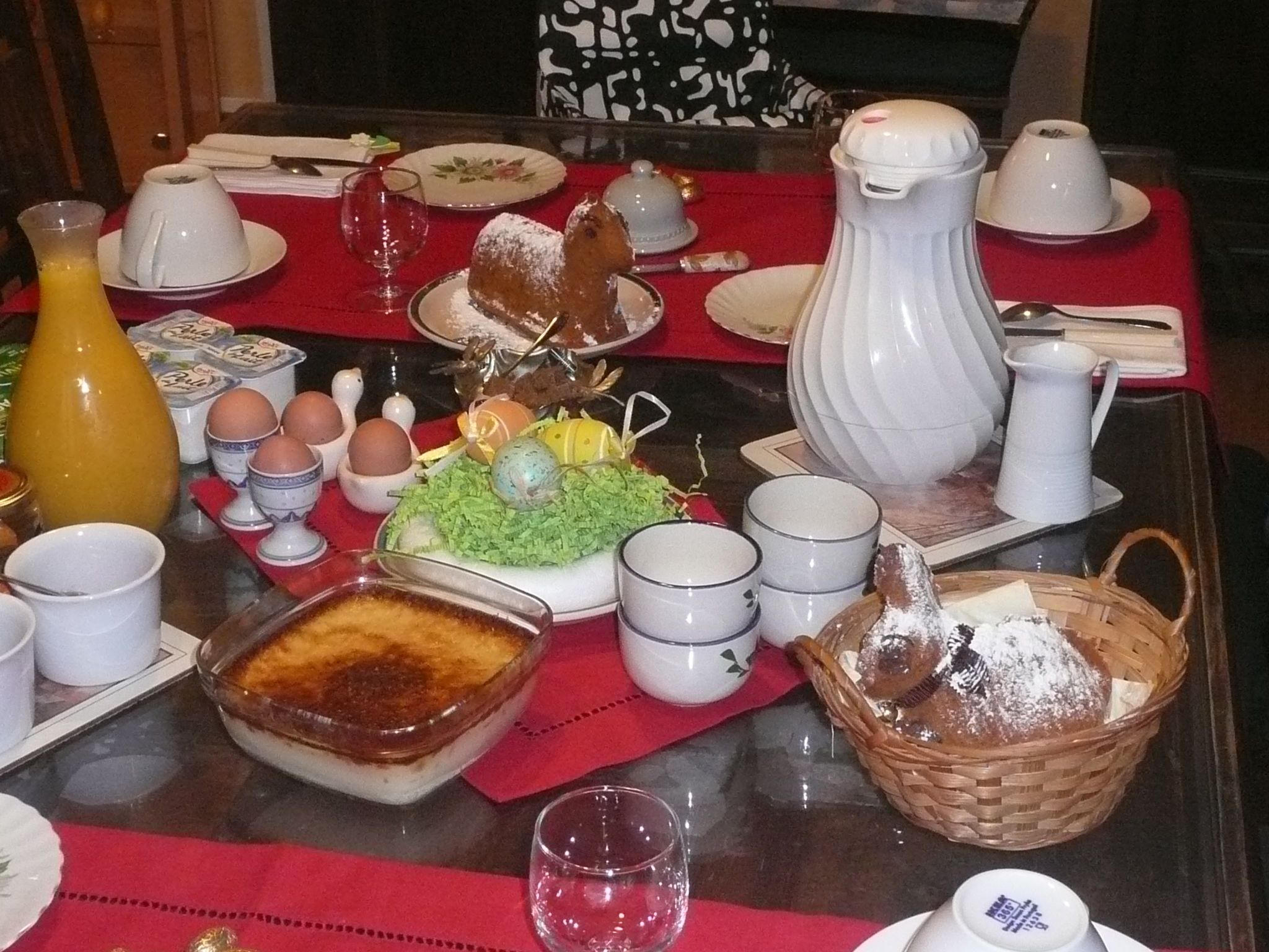 Una mesa de desayuno con diversos platos, como huevos, pastelería y una presentación de frutas.