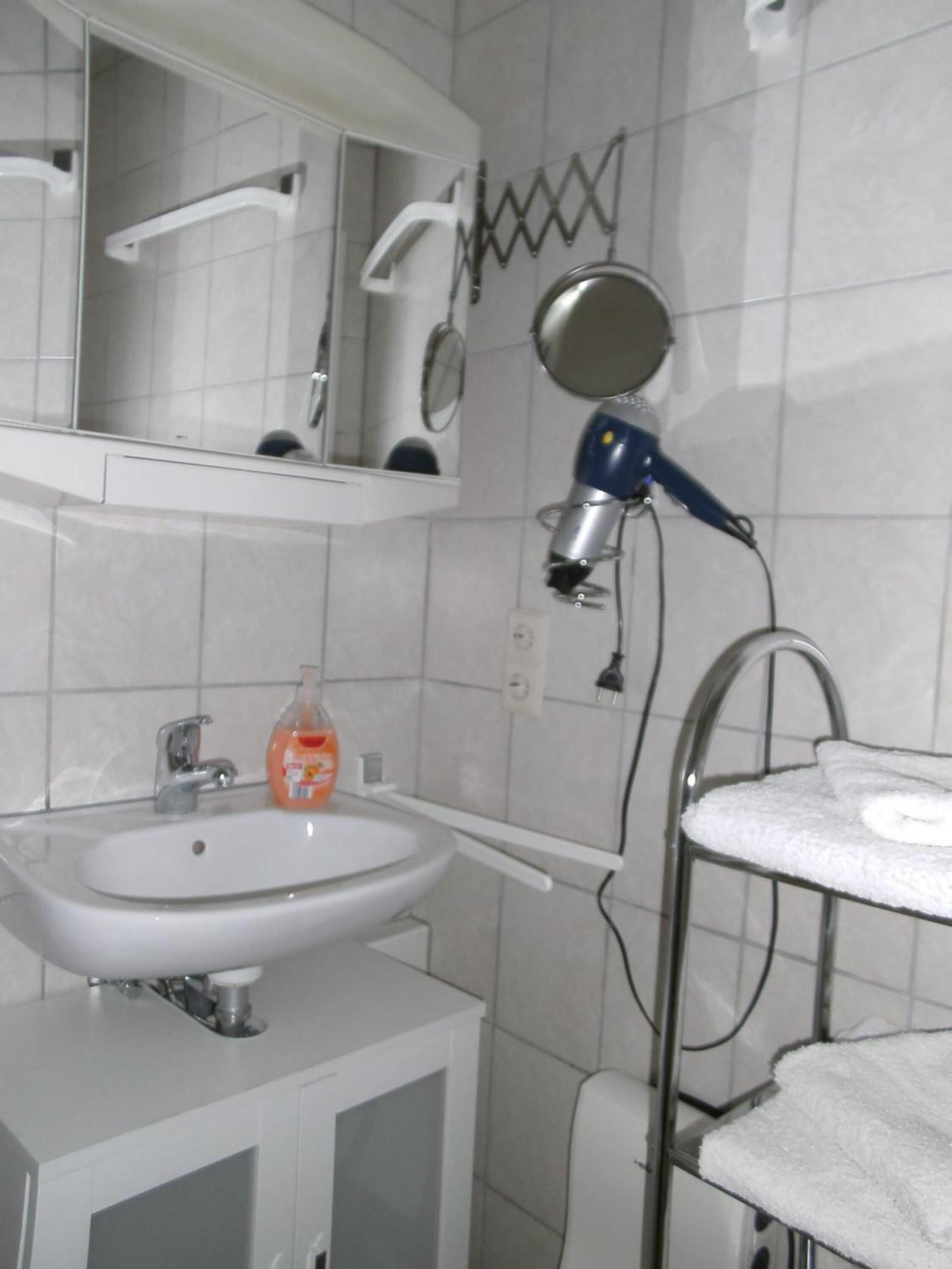 A bathroom with a white sink, mirror, and towel rack.