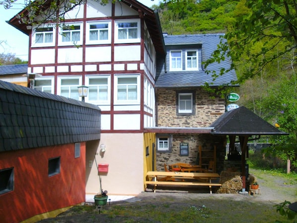 Ein traditionelles Fachwerkhäuschen mit Steinaußenwand, einer hölzernen Bank davor und einem Schild, das ein Restaurant anzeigt.
