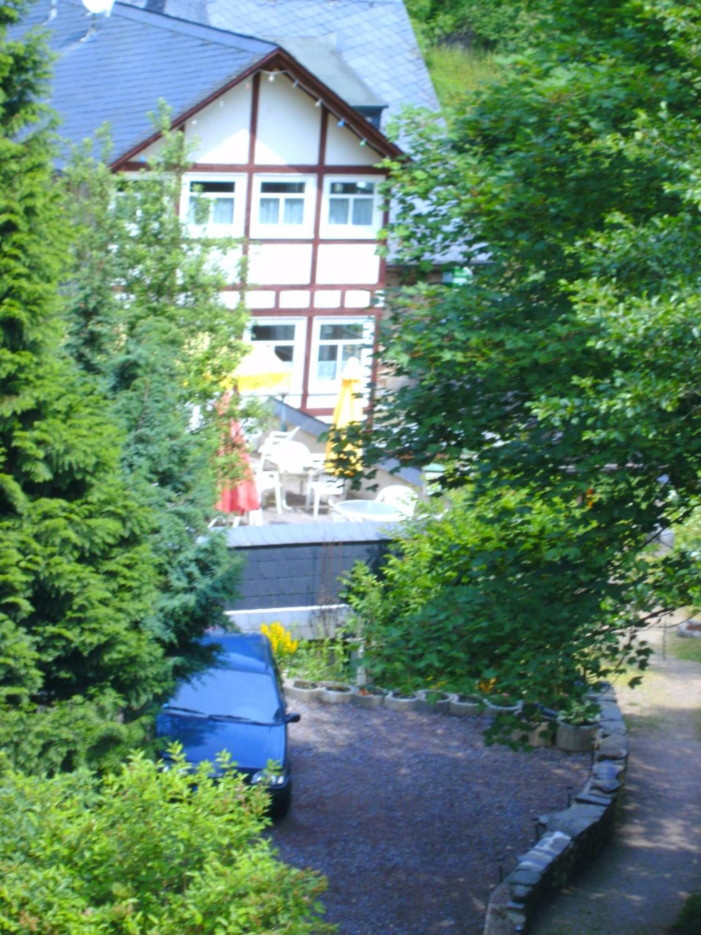 Une maison traditionnelle à colombages, avec une allée gravillonnée et une voiture garée.