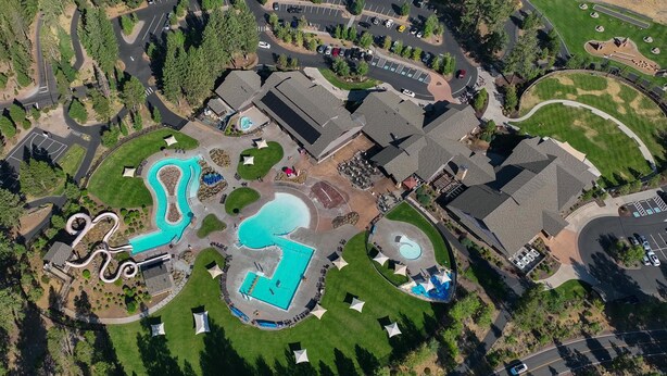 Vue aérienne d’un complexe hôtelier doté de plusieurs piscines, d’un terrain de golf et d’un parking.
