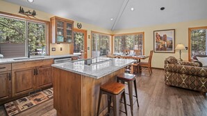 Une cuisine spacieuse dotée d’un grand îlot central, de meubles en bois et d’un coin repas avec une table et des chaises.