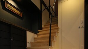 A staircase with wooden steps and a metal railing, leading to a white door. - Chizuruan (Kyoto)