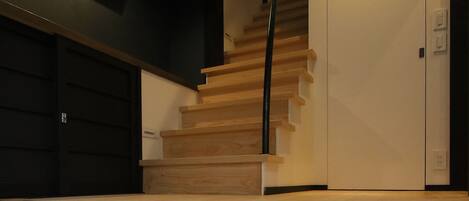 A staircase with wooden steps and a metal railing, leading to a white door.
