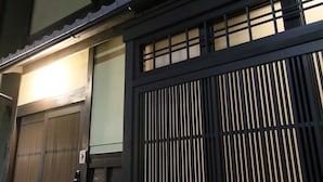 A traditional Japanese building with a large wooden gate, a circular window, and a tiled roof. - Chizuruan (Kyoto)