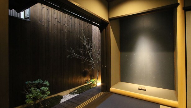 A modern interior with a wooden partition, a small plant, and a bench. - Chizuruan (Kyoto)