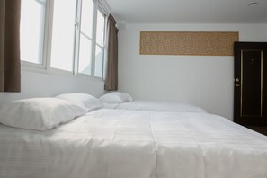 Una cama bien hecha con sábanas blancas, una ventana con cortinas y un panel decorativo en la pared.