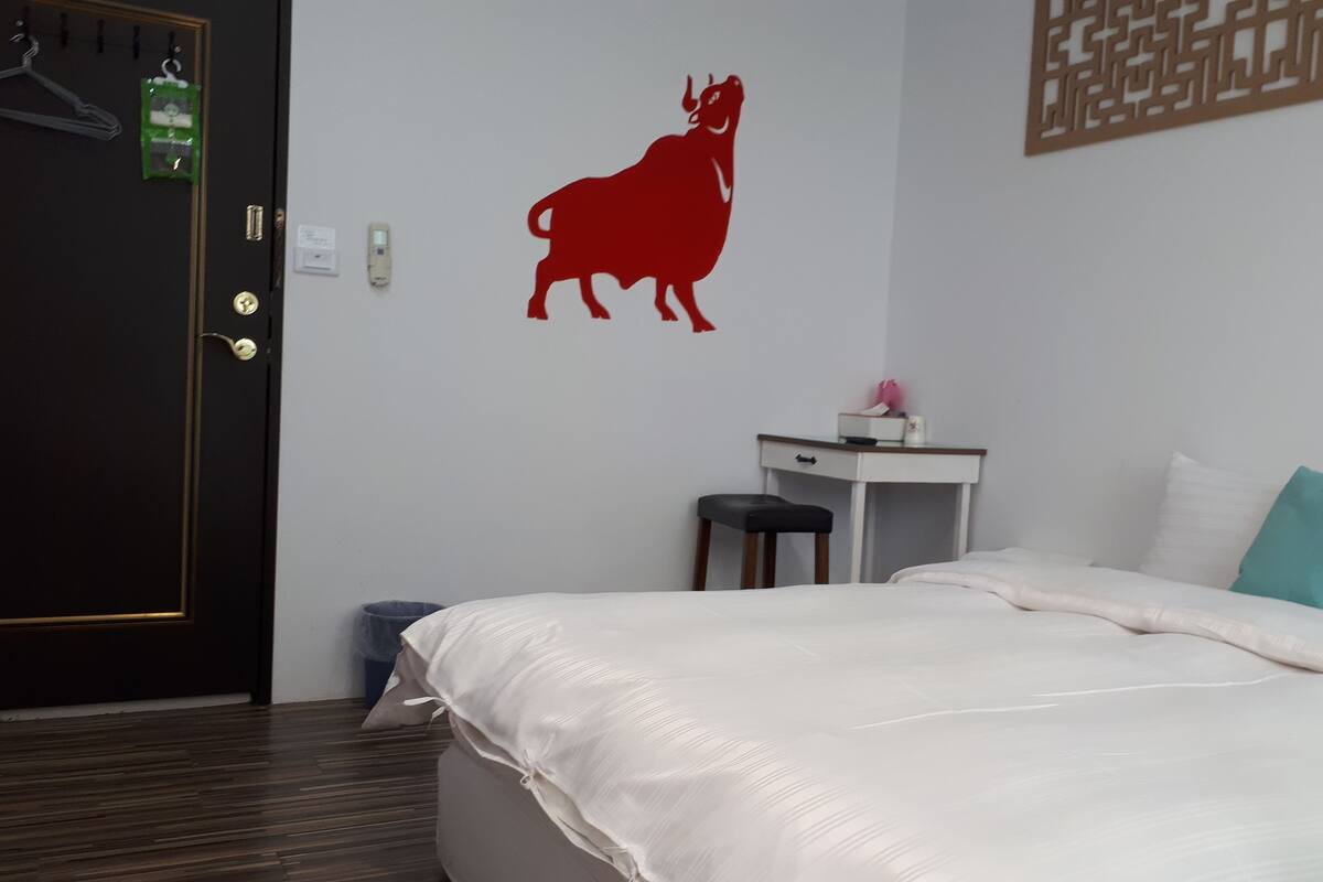 Un dormitorio con una cama, un escritorio, una silla, un perchero y una decoración de pared.