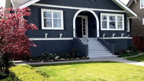 A two-story house with a dark exterior, white trim, and a front entrance with a staircase. - Sunny Family Home in Heart of Kitsilano with Mountain Views (Vancouver)