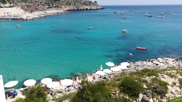 A coastal view with clear turquoise waters, rocky shorelines, and several boats.