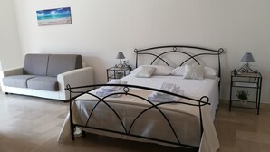 A neatly arranged bedroom with a bed, a sofa, and two bedside tables.