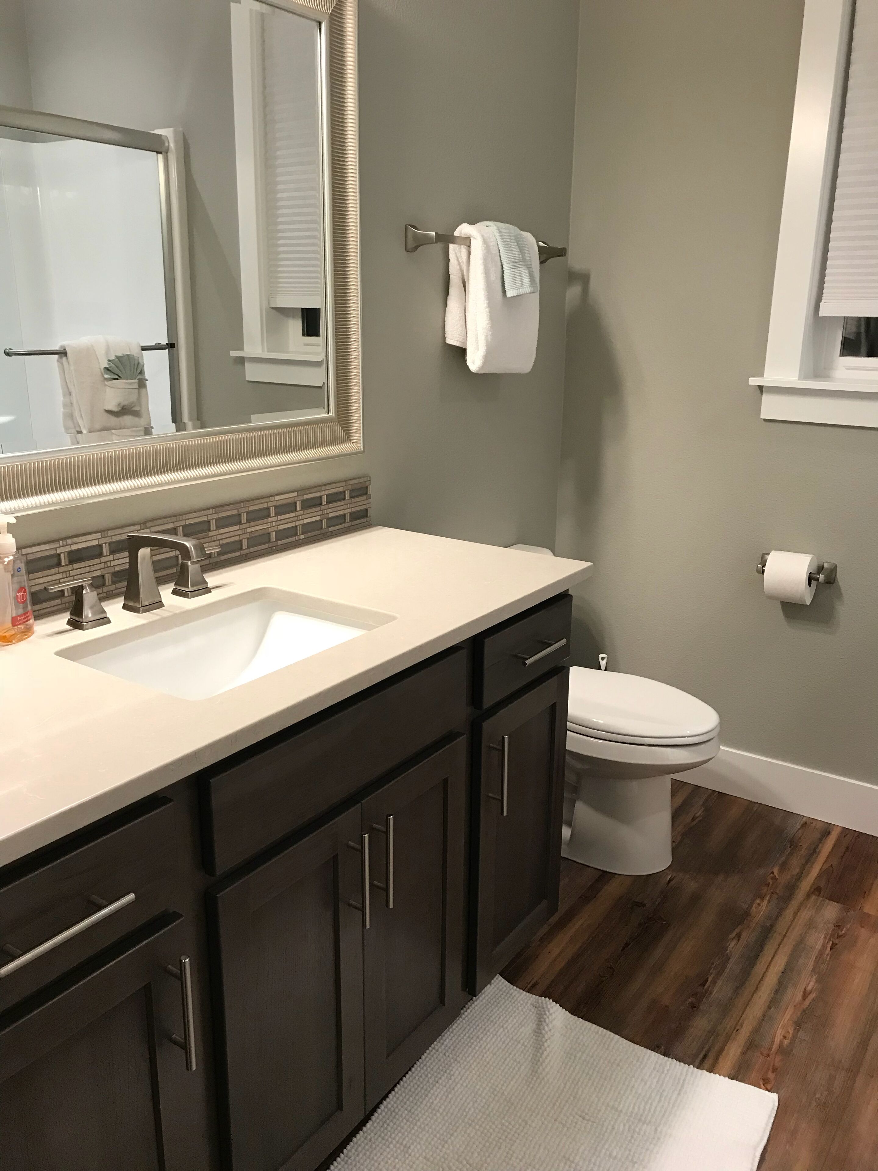 A bathroom with a double sink vanity, a toilet, a mirror, and a towel rack.