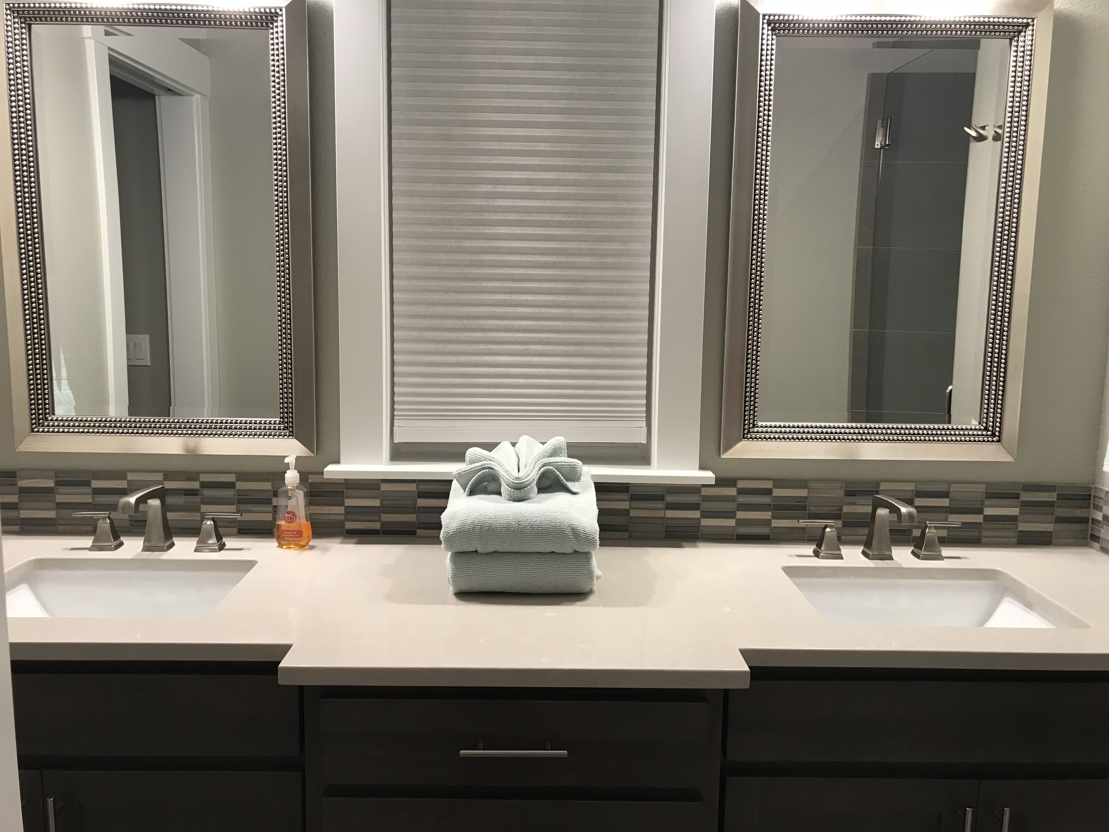 A bathroom with two sinks, a towel, and a bottle of soap.