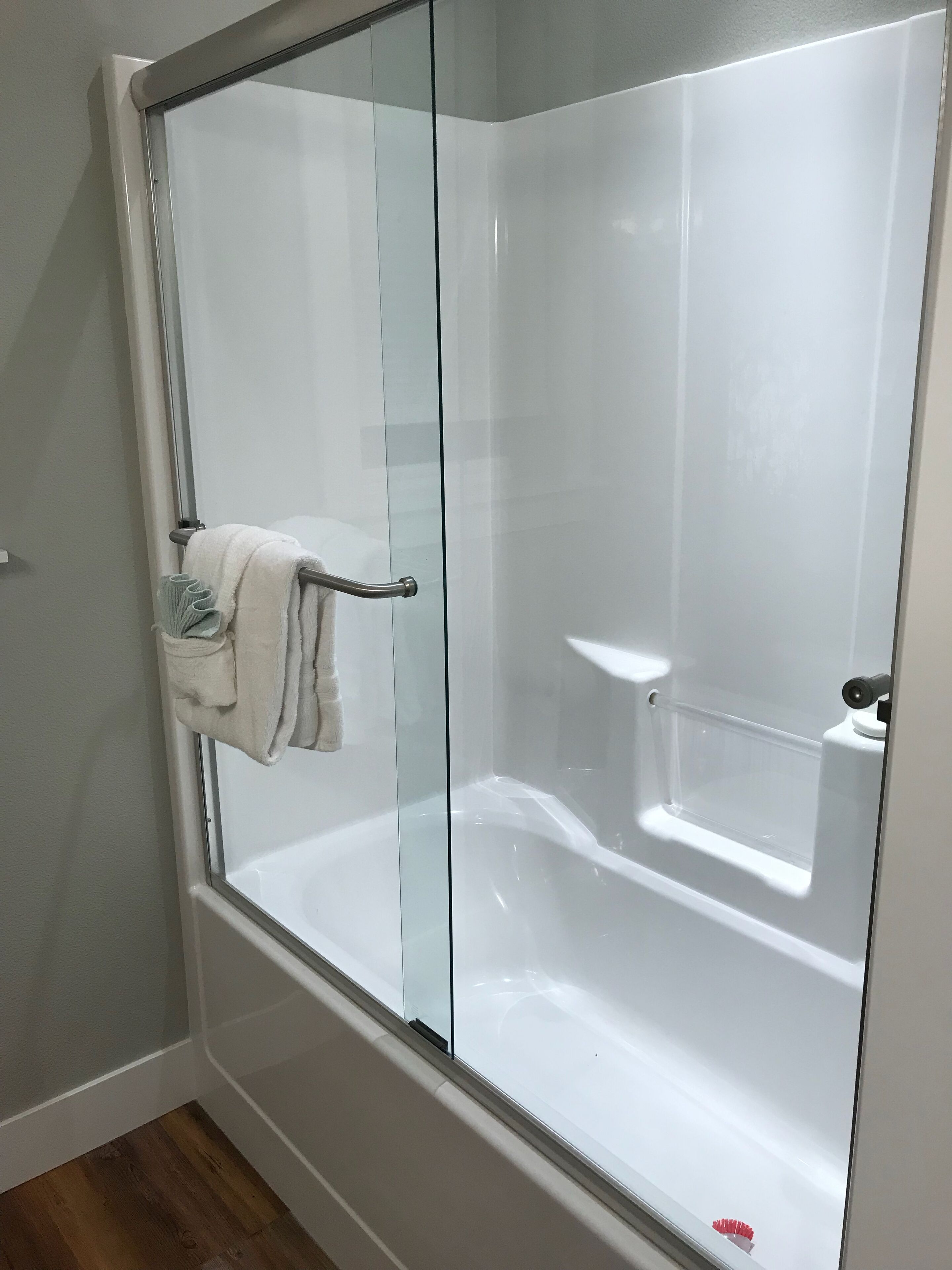 Un box de ducha moderno con puerta de cristal, un perchero y un estante empotrado.