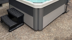 Un jacuzzi en un patio trasero con una casa al fondo.