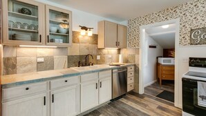 Eine moderne Küche mit hellen Holzschränken, einer Steinrückwand und Holzboden.