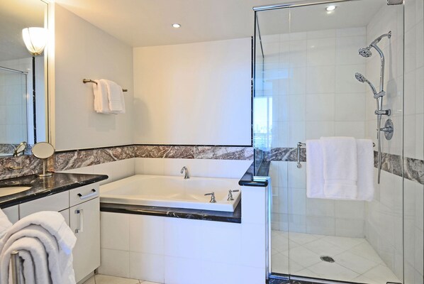 A modern bathroom with a bathtub, a glass-enclosed shower, and a vanity with a sink and mirror.