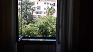 A room with a window overlooking a building with a dome and trees in the foreground. - Lady Ida (Vietri sul Mare)
