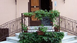 A building entrance with a wooden door, a small balcony with a metal railing, and steps leading up to the door. - Lady Ida (Vietri sul Mare)