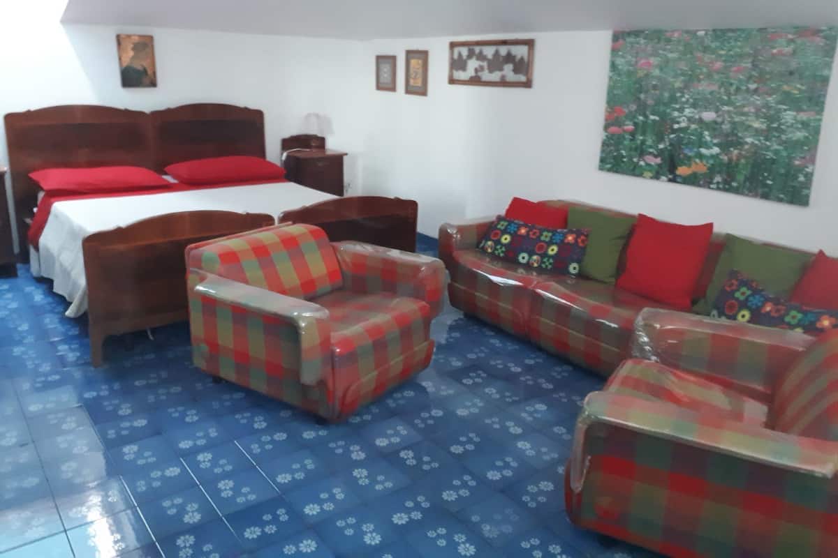 A room with a bed, two chairs, a sofa, and a small table.