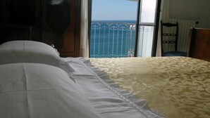 A hotel room with a bed, a chair, and a view of the sea through a balcony with a metal railing. - Lady Ida (Vietri sul Mare)