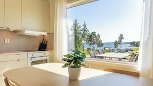 A modern kitchen with a large window overlooking a lakeside view. - Gullviks Havsbad (Domsjö)