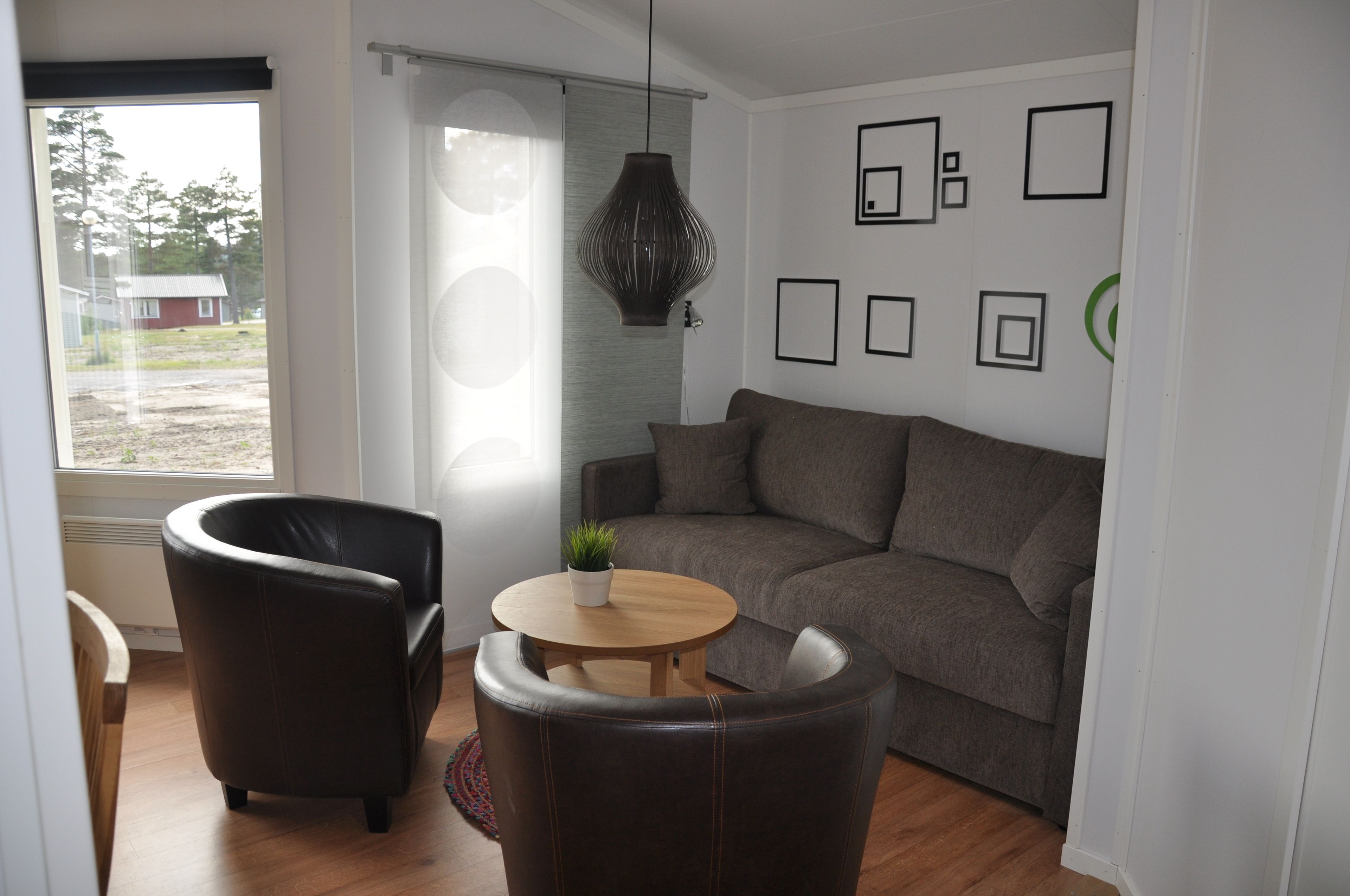 A modern living room with a sofa, two armchairs, a small wooden table, and a potted plant.