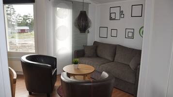 A modern living room with a sofa, two armchairs, a small wooden table, and a potted plant.