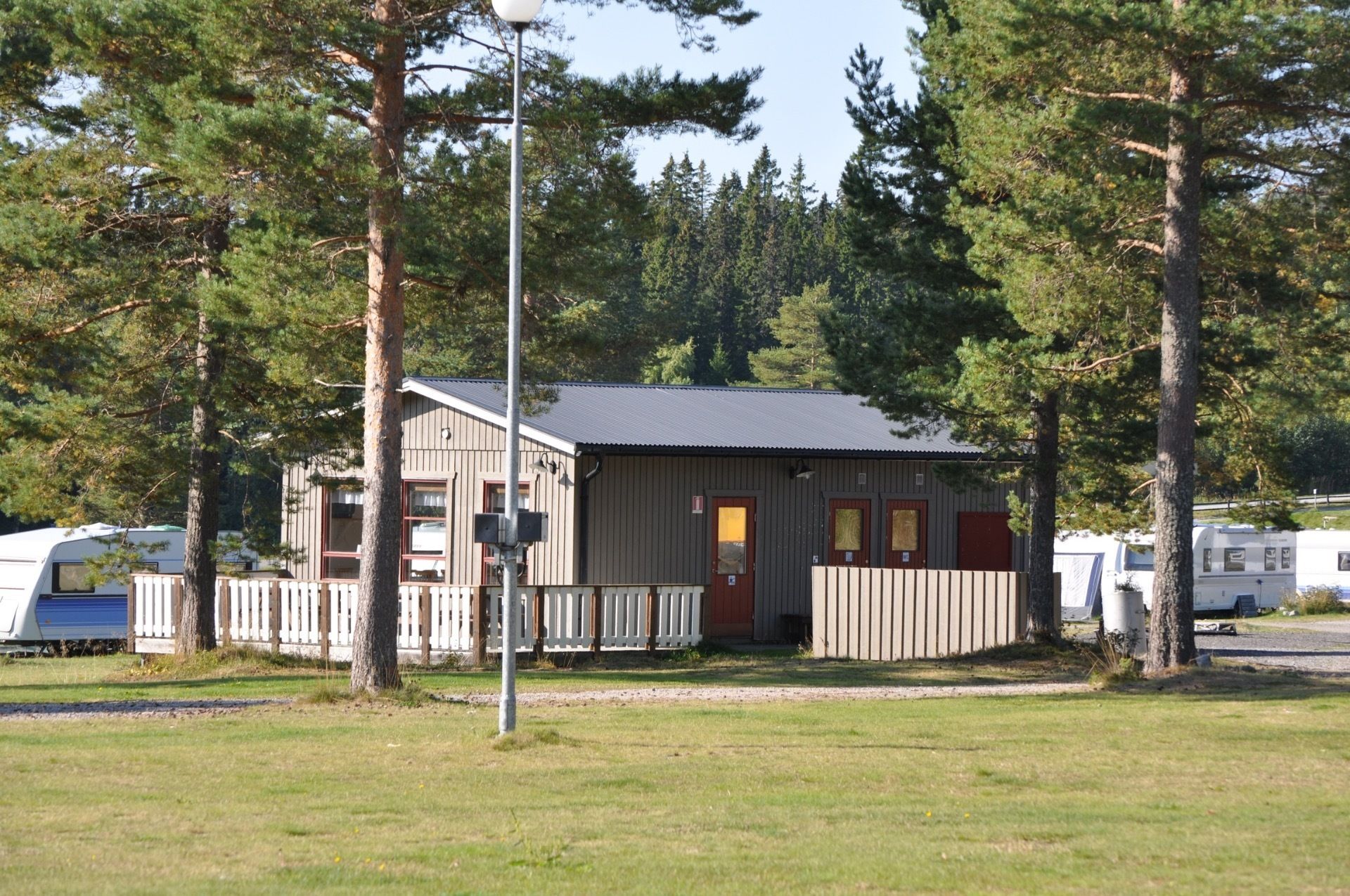 A small cabin with a fenced yard, surrounded by trees.