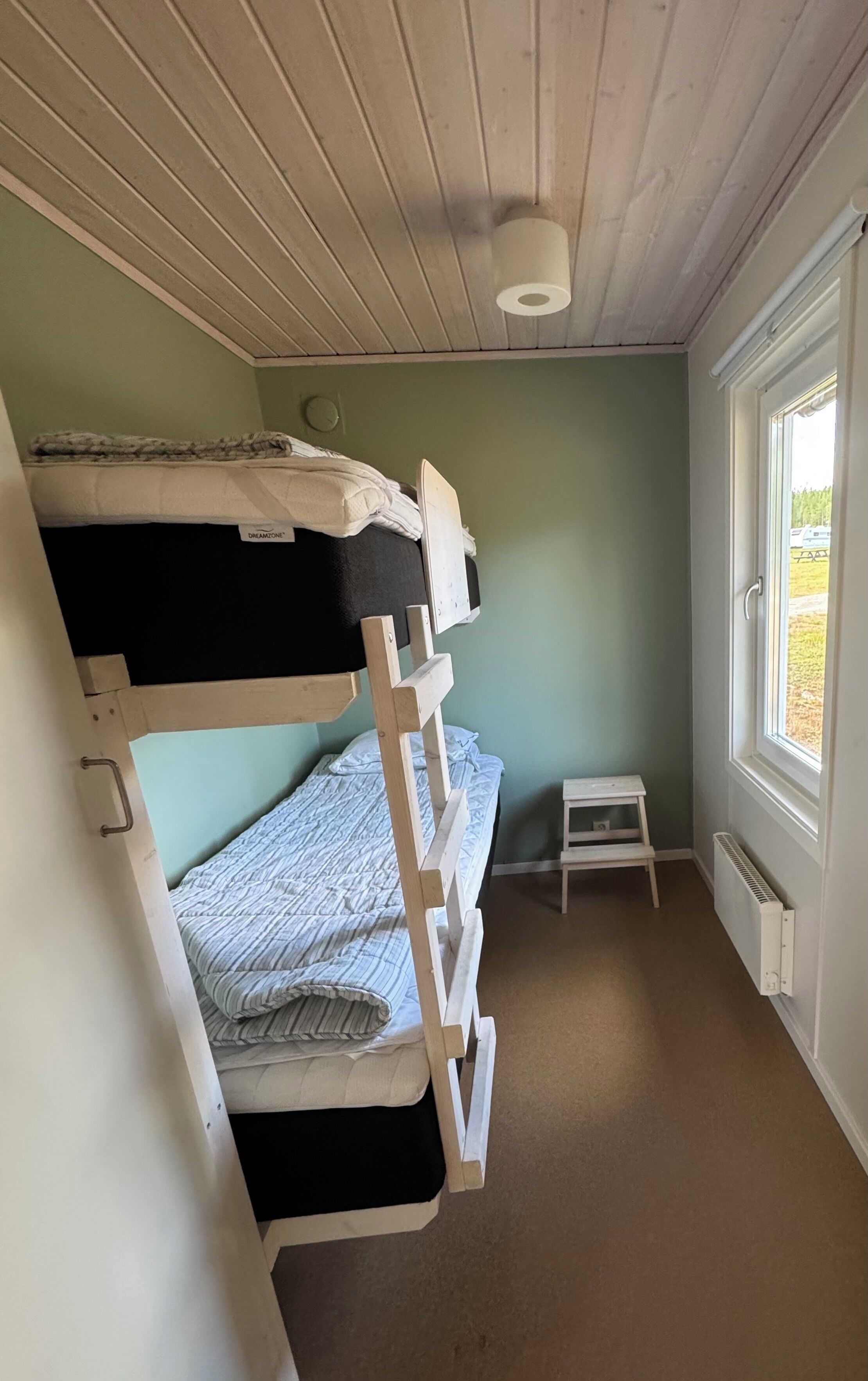 A bunk bed room with a small table and a window.