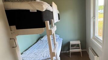 A bunk bed room with a small table and a window.