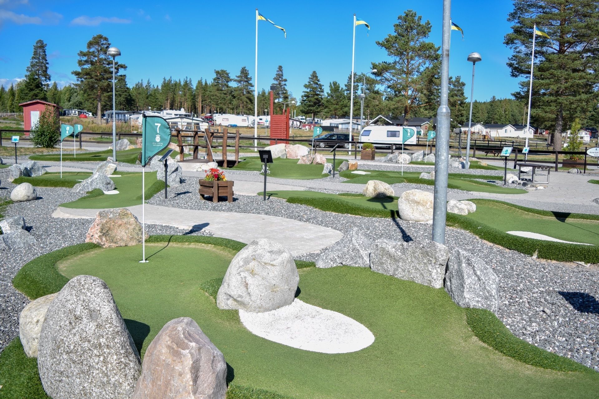 A miniature golf course with a green fairway, sand traps, and large rocks.