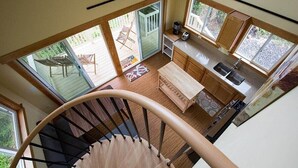 Una escalera de caracol conduce a una cocina con un toldo de vidrio que da a un patio.