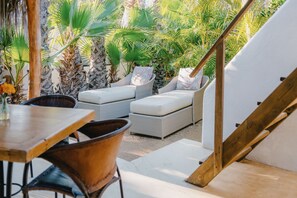 Un patio con mobiliario de mimbre, una mesa de madera y una estructura de carpa blanca.